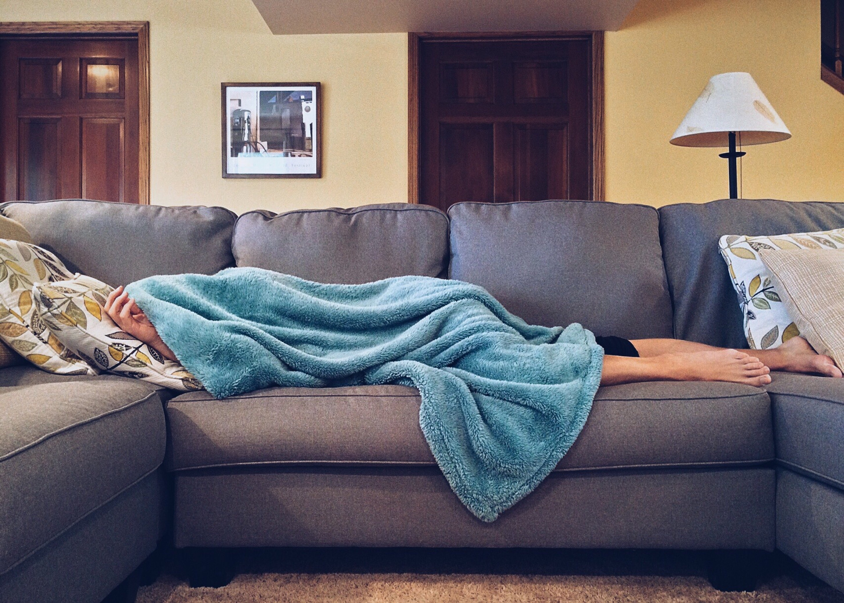 Person lying on couch looking unwell