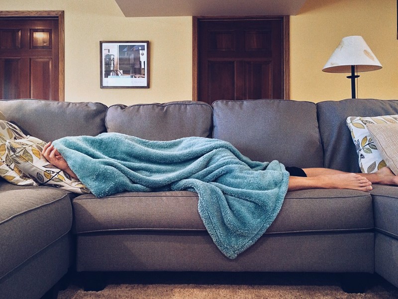 Person lying on couch looking unwell