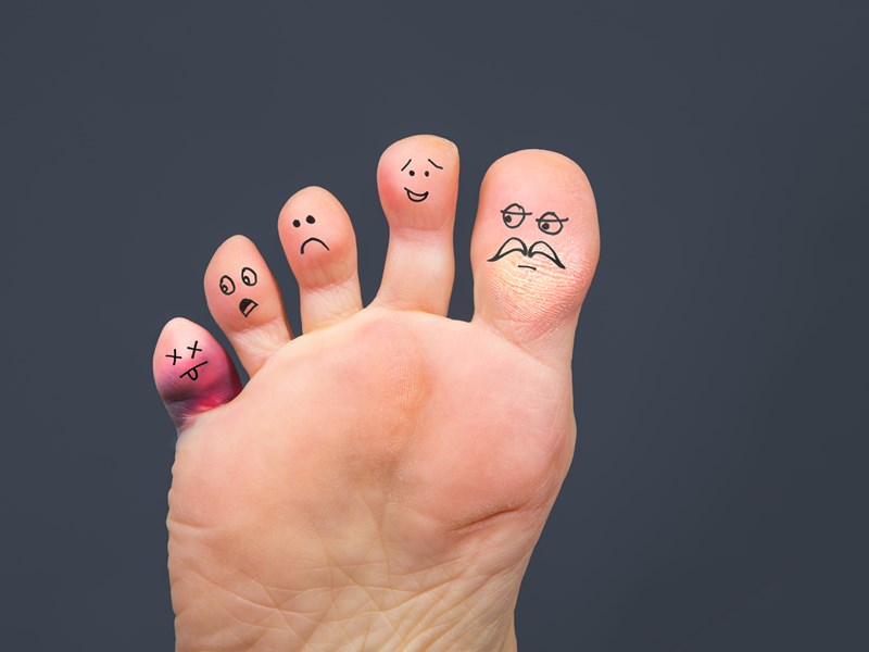 Happy and sad faces drawn on the toes of a persons foot