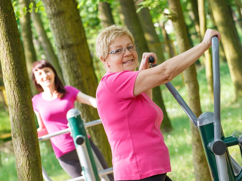 Two women exercising on equipment outdoors