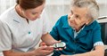 Diabetes nurse testing blood glucose of elderly patient