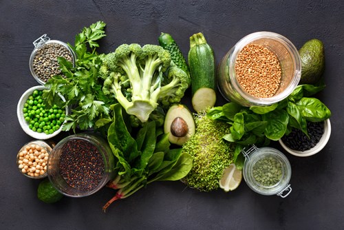 Raw healthy food clean eating vegetables and grain products: green vegetables, quinoa, chickpea, beans, buckwheat, green lentils on dark stone background